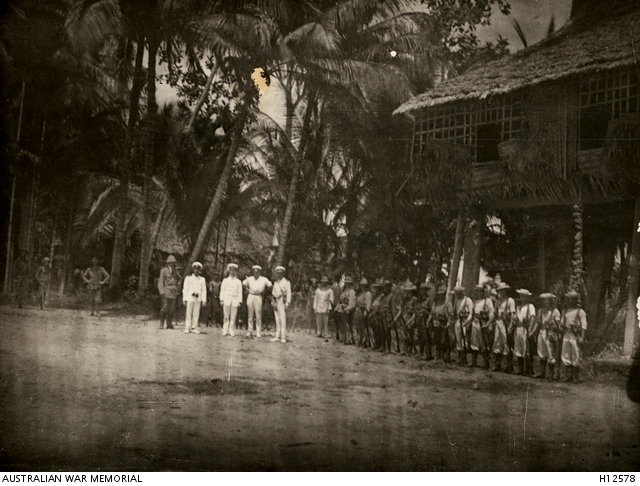 Angorum, New Guinea. 16 December 1914. The Australian flag being raised with an official party standing by as the Proclamation advising the Australian Naval and Military Expeditionary Force was taking control of the country from the German Force was being read. 